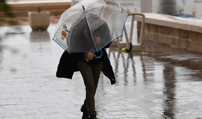 Una dona es protegeix de la pluja baix un paraigua.