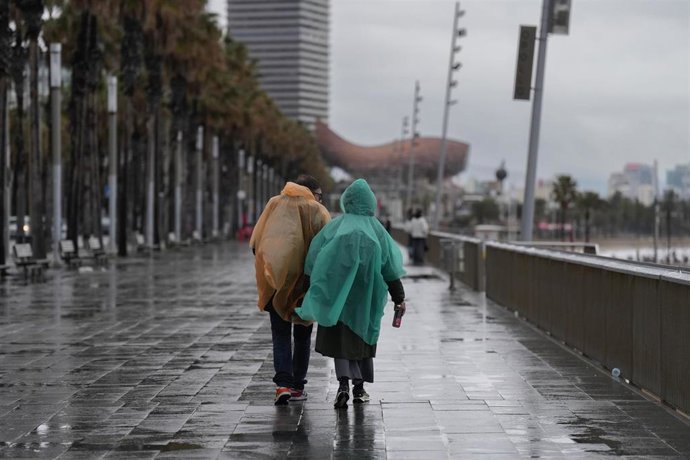 Archivo - Vecinos de Barcelona pasean bajo la lluvia en la playa de la Barceloneta durante el temporal, a 19 de enero de 2026, en Barcelona, Cataluña (España). 