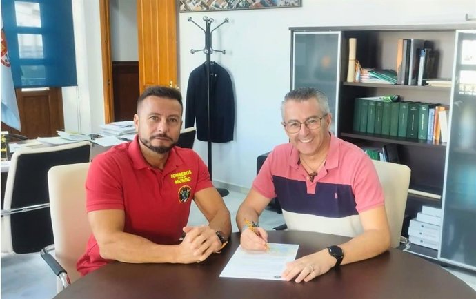 El alcalde de Villanueva del Ariscal, Francisco García (d), tras el acuerdo firmado con la Organización de Bomberos para el Mundo, representada por Eugenio Mantero, en una foto de archivo