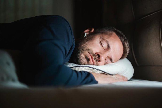 Archivo - Hombre joven durmiendo con auriculares en la cama