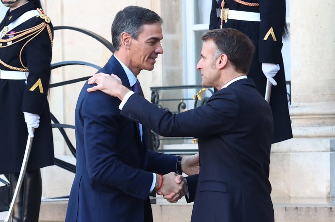 El presidente del Gobierno, Pedro Sánchez (i), es recibido por el presidente de Francia, Emmanuel Macron (d), a su llegada a la reunión de la Coalición de Voluntarios que se celebra en el Palacio del Elíseo, a 6 de enero de 2026, en París (Francia).