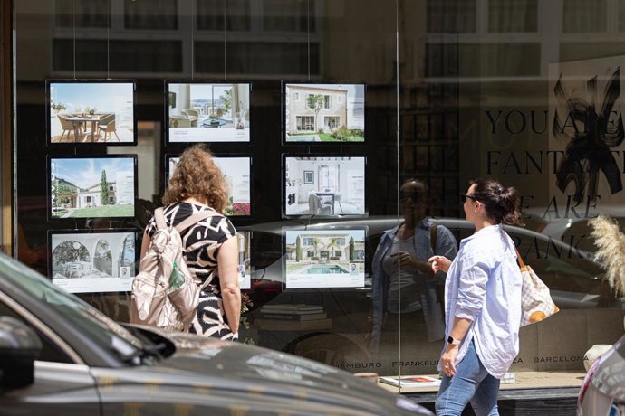 Archivo - Dos personas observan los anuncios de viviendas en venta en una inmobiliaria de Palma.