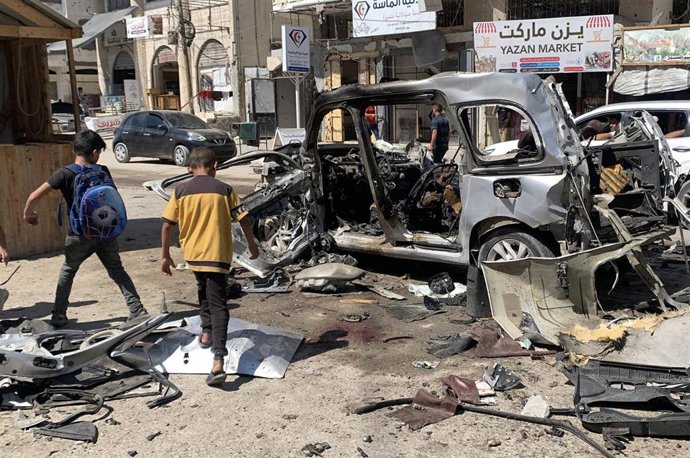 Dos niños junto a un coche destruido tras un ataque de Israel.