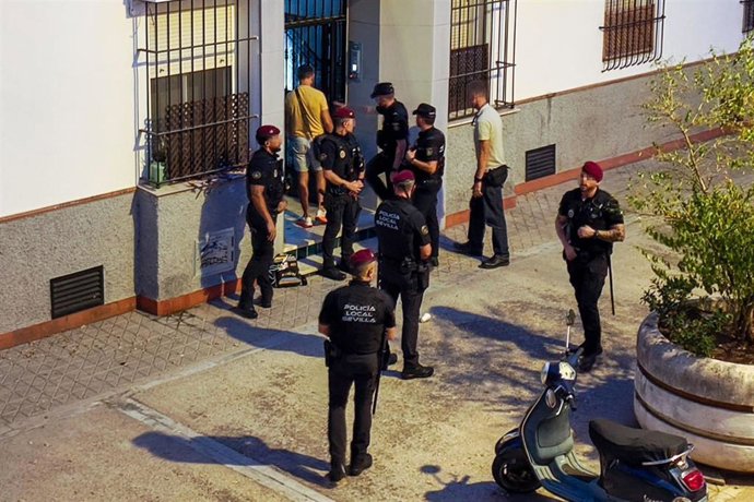 Agentes de la Policía Nacional y de los GAR de la Policía Local de Sevilla en la puerta de la vivienda del barrio de los Remedios donde ha sido hallado sin vida un menor de 10 años.