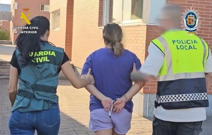 Una guardia civil y un policía local de Cáceres custodian a una detenida en la operación.