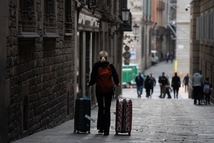 Archivo - Una persona amb dues maletes a Barcelona