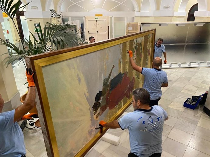 Operarios descolgando la obra 'España llevando la gloria a Filipinas', de Juan Luna Novicio, del Ayuntamiento de Cádiz para su envío al Museo del Prado.