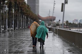 Archivo - Arxiu - Veïns de Barcelona passegen sota la pluja a la platja de la Barceloneta durant el temporal de gener
