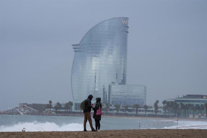 Archivo - Vecinos de Barcelona pasean bajo la lluvia en la playa de la Barceloneta durante el temporal, a 19 de enero de 2026, en Barcelona, Cataluña (España). 