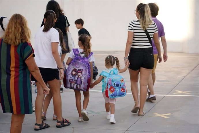 Archivo - Niños y padres hacen cola para entrar al colegio.