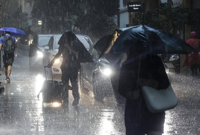Archivo - Imagen de archivo de varias personas protegiéndose de la lluvia con un paraguas