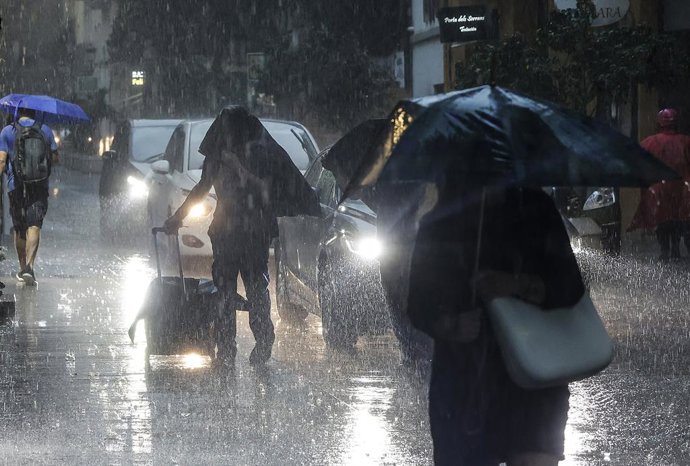 Archivo - Arxiu - Imatge d'arxiu de diverses persones protegint-se de la pluja amb un paraigua