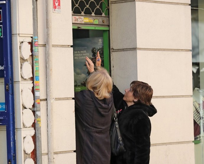 Archivo - Dos mujeres abriendo la persiana de su negocio