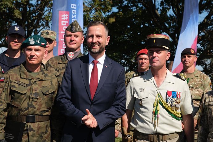 Archivo - Arquivo – 15 de agosto de 2026, Varsóvia, Voivodia da Mazóvia, Polônia: O ministro da Defesa polonês, WLADYSLAW KOSINIAK-KAMYSZ, posa para uma foto em grupo com soldados poloneses e estrangeiros aliados em frente a uma placa com o slogan “SAFE P