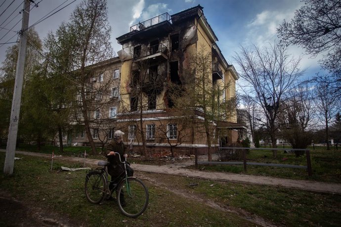 Archivo - Arquivo - 29 de abril de 2026, Shostka, Sumy, Ucrânia: Um morador, de bicicleta, observa um prédio destruído e carbonizado após um ataque de drones russos em Shostka, na parte norte da região de Sumy.