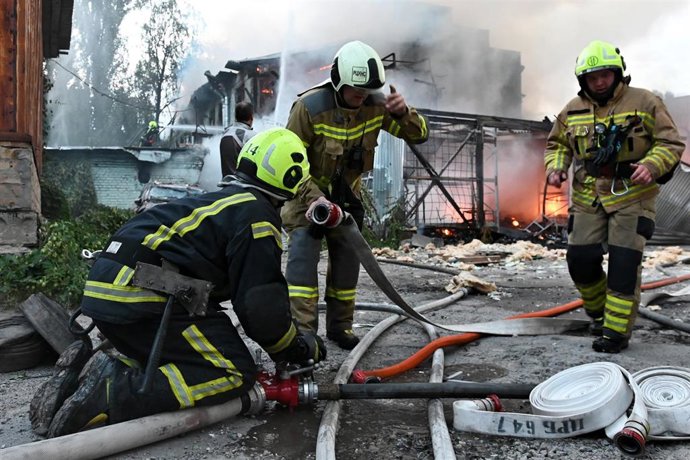 Bomberos ucranianos trabajando en una zona afectada por los bombardeos rusos en Kiev.