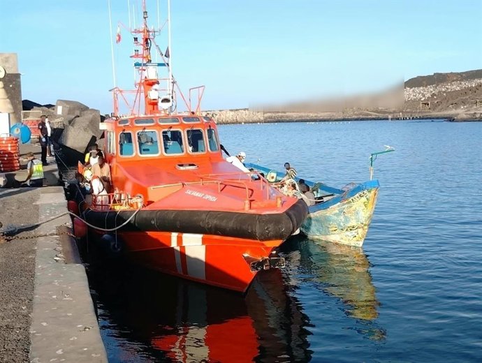 Un cayuco junto a una embarcación de Salvamento Marítimo en el puerto de La Restinga