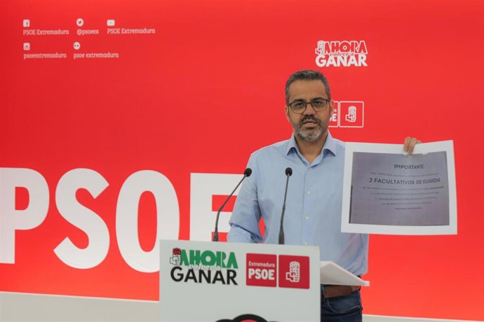 El portavoz del PSOE de Extremadura, Manuel José González Andrade, muestra una copia del cartel de las Urgencias del Hospital San Pedro de Alcántara de Cáceres.