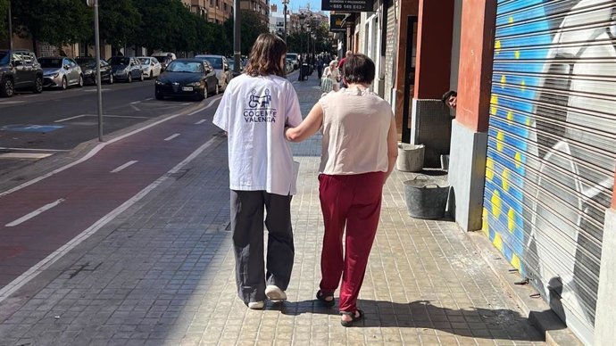 Archivo - Una voluntaria de COCEMFE Valencia acompaña a una persona con necesidadesd de apoyo.