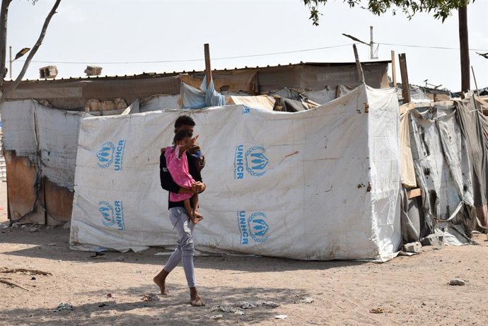 Archivo - ADEN, Aug. 19, 2025  -- A displaced man holding his child walks beside tents at a temporary displacement camp on the outskirts of Aden, Yemen, Aug. 11, 2025.   As the World Humanitarian Day is marked across countries on Tuesday, the Middle East 