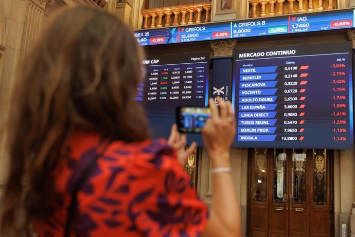 Archivo - Una persona fotografía paneles del Ibex 35 en el Palacio de la Bolsa, a 22 de septiembre de 2023, en Madrid (España). 