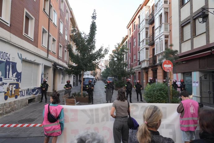 Vecinos sujetan una pancarta frente a los agentes de la Ertzaintza mientras intentan paralizar un desahucio, a, en Vitoria-Gasteiz