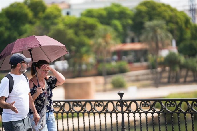 Dos personas con sombrilla y ropa veraniega durante una jornada de intenso calor. A 03 de septiembre de 2026, en Sevilla (Andalucía, España).