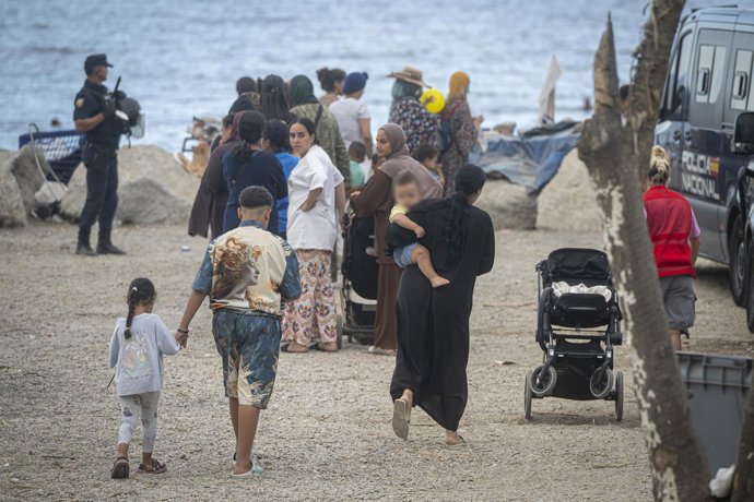 Varios migrantes recogen comida y bebida de Cruz Roja en la playa del Trampolín, a 23 de septiembre de 2026, en Ceuta (España). Embarcaciones de Salvamento Marítimo han trabajado este miércoles en la reparación de desperfectos detectados en la barrera neu