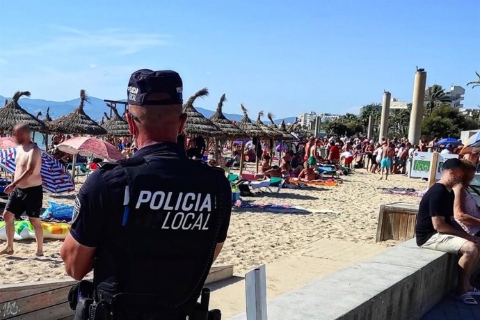 Archivo - Un policía local vigila un tramo de Playa de Palma.