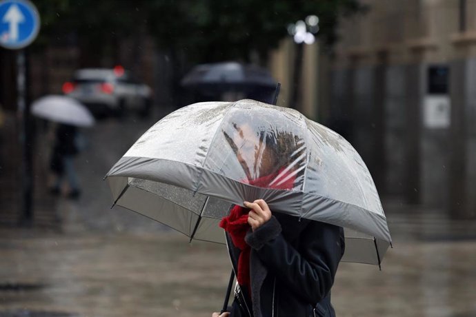 Archivo - Transeúnte por el centro de Málaga protegiéndose de la lluvia.
