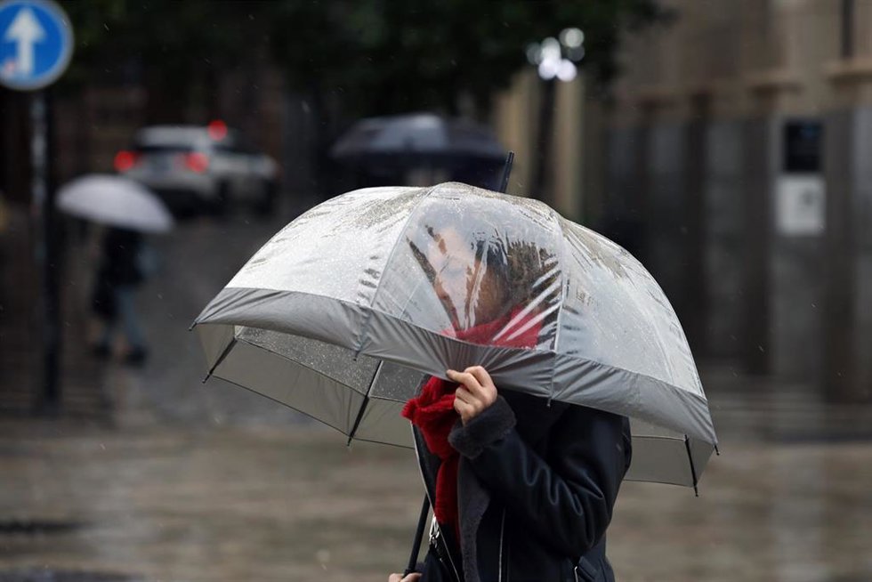 Archivo - Transeúnte por el centro de Málaga protegiéndose de la lluvia.