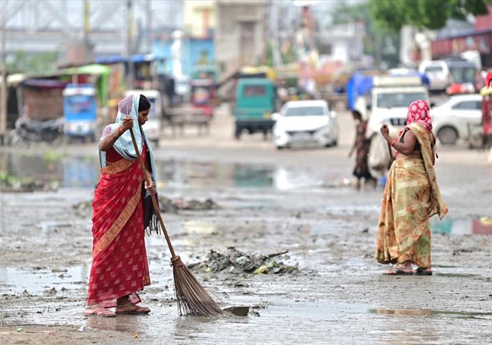 Dos mujeres limpian un área afectada por el desbordamiento de un río, en Prayagraj, noreste de India.