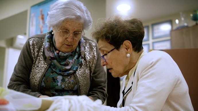 Una mujer mayor acompañada por una voluntaria de la Sociedad San Vicente de Paúl.
