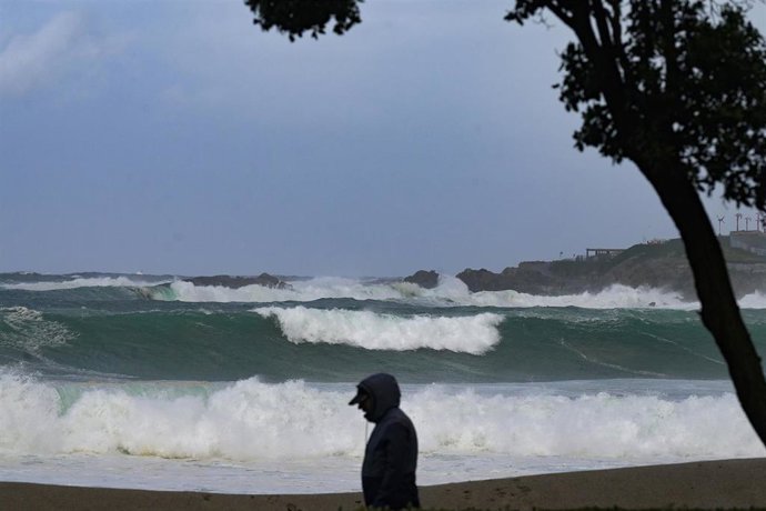 Archivo - Una persona camina delante de las olas durante el frente meteorológico, a 23 de febrero de 2024, en A Coruña, Galicia.