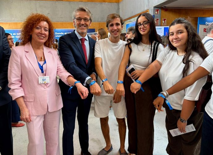 El consejero de Empleo, Luis Alberto Marín; la directora del SEF, Pilar Valero, y un grupo de asistentes a la V Feria de Empleo muestran las pulseras digitales que permiten entregar el CV de manera telemática