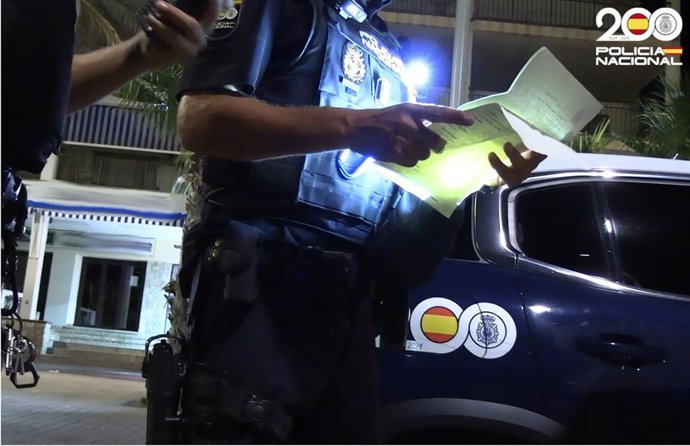 Agente de la Policía Nacional, de noche, en Playa de Palma, con un expediente.