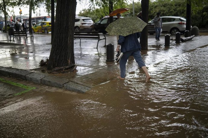 Una mujer cruza a través de la lluvia acumulada en la calle en el barrio de Canyelles-Nou Barris, a 29 de septiembre de 2026, en Barcelona, Catalunya (España).