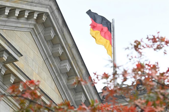 Archivo - FILED - 10 October 2025, Berlin: A German flag can be seen behind the autumnal leaves of a tree on the Reichstag building. Photo: Niklas Graeber/dpa