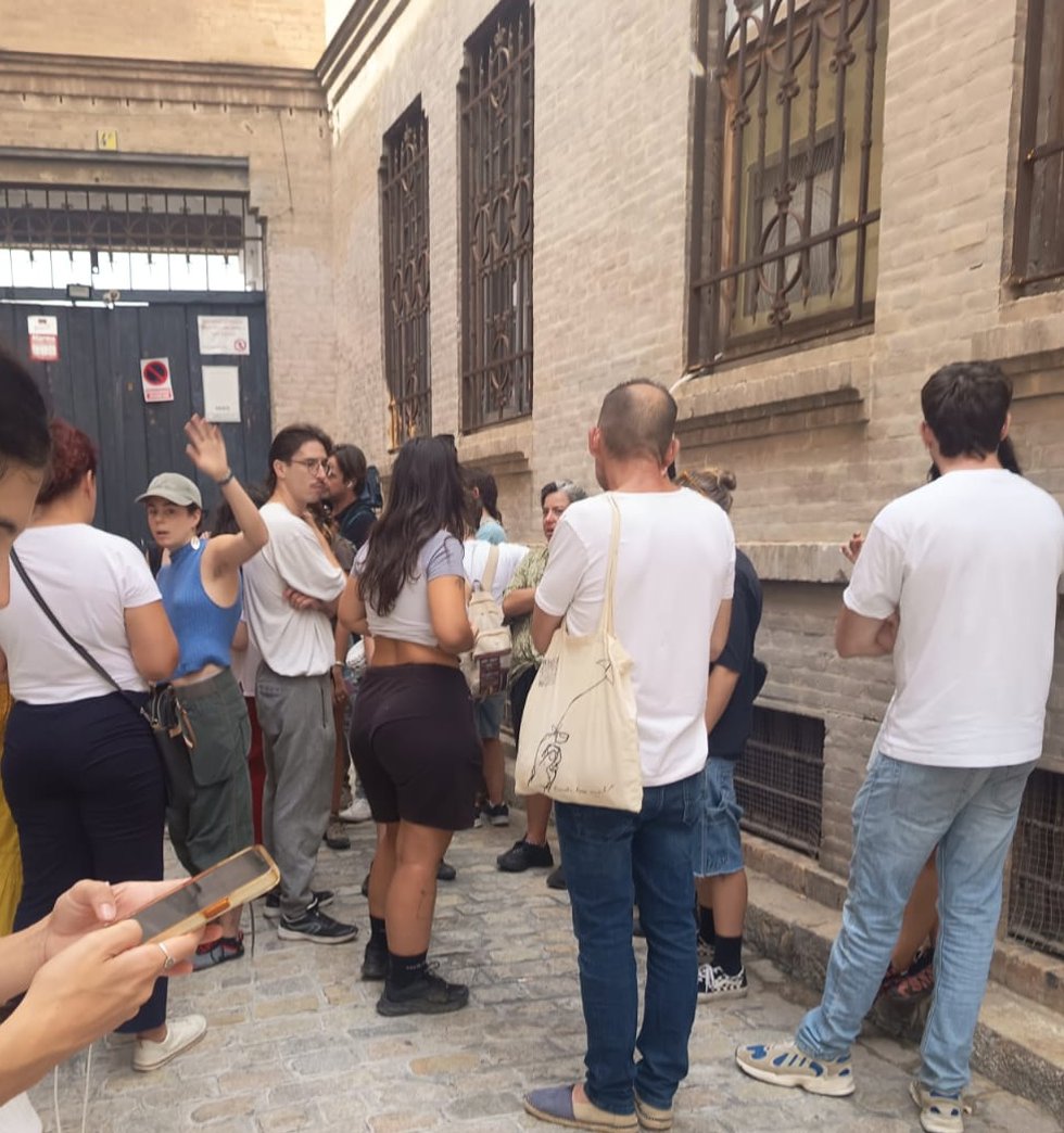 Vecinos en las puertas de la antigua Fábrica de Sombreros de Sevilla tras el aviso de un nuevo desalojo.