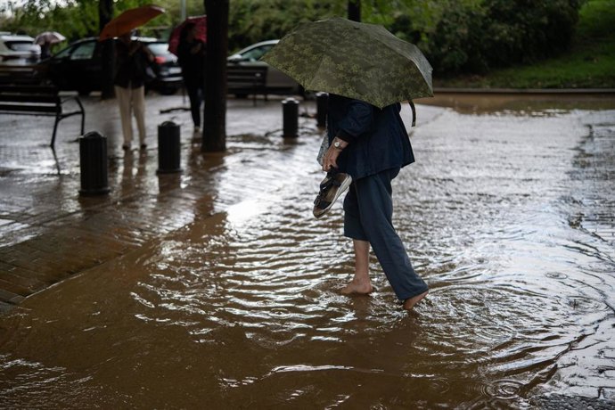 Una dona creua a través de la pluja acumulada. 