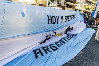 Archivo - Manifestantes sostienen una bandera argentina con la imagen de las Islas Malvinas