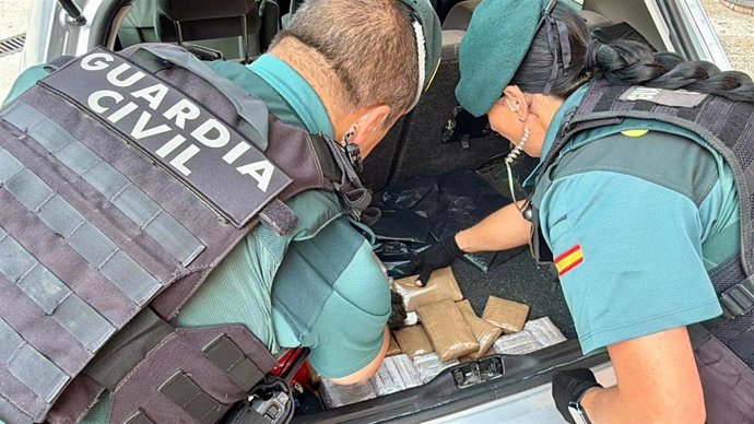 Agentes de la Guardia Civil inspeccionan los paquetes de hachís localizados en el maletero del coche.