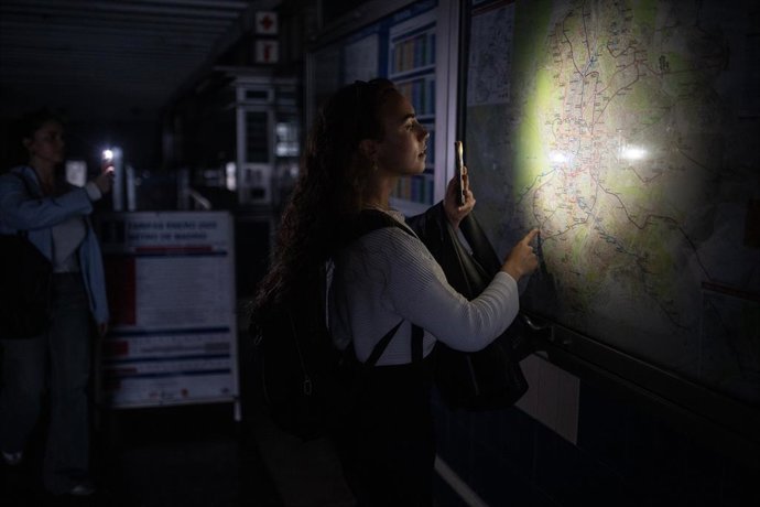 Archivo - Arquivo - Uma mulher ilumina com a lanterna do celular um mapa da rede do Metrô de Madri em uma estação, em 28 de abril de 2025, em Madri, Espanha.  Alejandro Martínez Vélez / Europa Press 28/4/2025