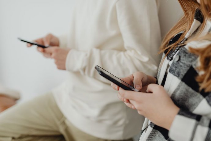 Primer plano de dos personas usando smartphones en interiores