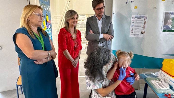 María Jesús Campos (centro) y Diego Copé (dcha.) asisten a la vacunación contra la gripe de una niña en un colegio de Córdoba.
