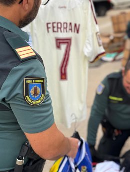 Efectivos de la Guardia Civil, ante una camiseta de la Selección Española de Fútbol, presuntamente falsificada.