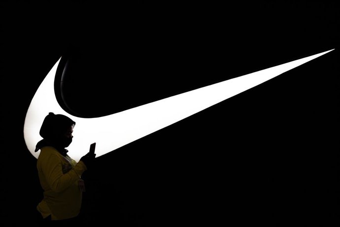 Archivo - Arquivo - Mulher caminhando em frente ao logotipo da Nike em Jacarta (Indonésia).