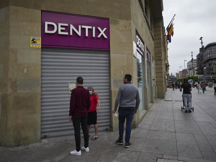 Archivo - Una mujer se apoya en la puerta de una clínica Dentix.