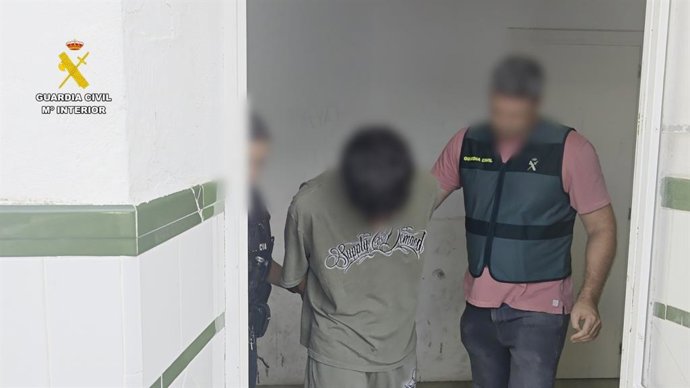 Un agente de la Guardia Civil, con uno de los detenidos