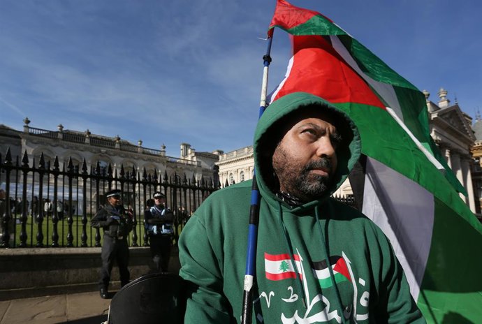 Archivo - Arquivo - 1º de março de 2025, Cambridge, Inglaterra, Reino Unido: Um manifestante segura uma bandeira palestina em frente à Senate House da universidade durante o protesto, sob o olhar de policiais. Manifestantes pró-palestinos se reúnem após a